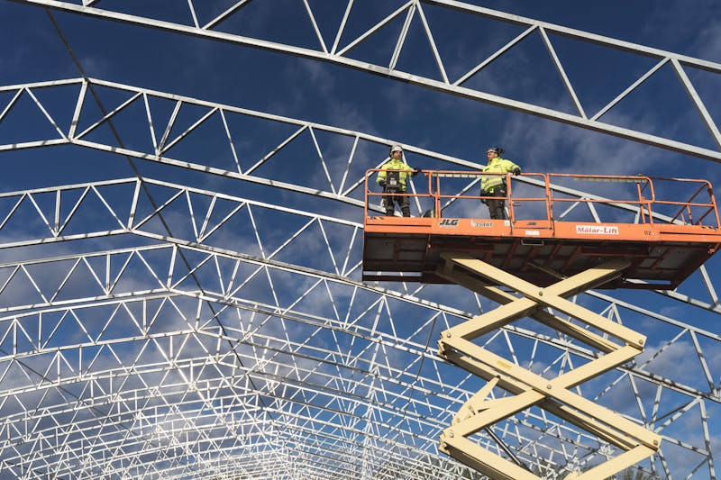 Workers on scissor lift at active racking teardown site