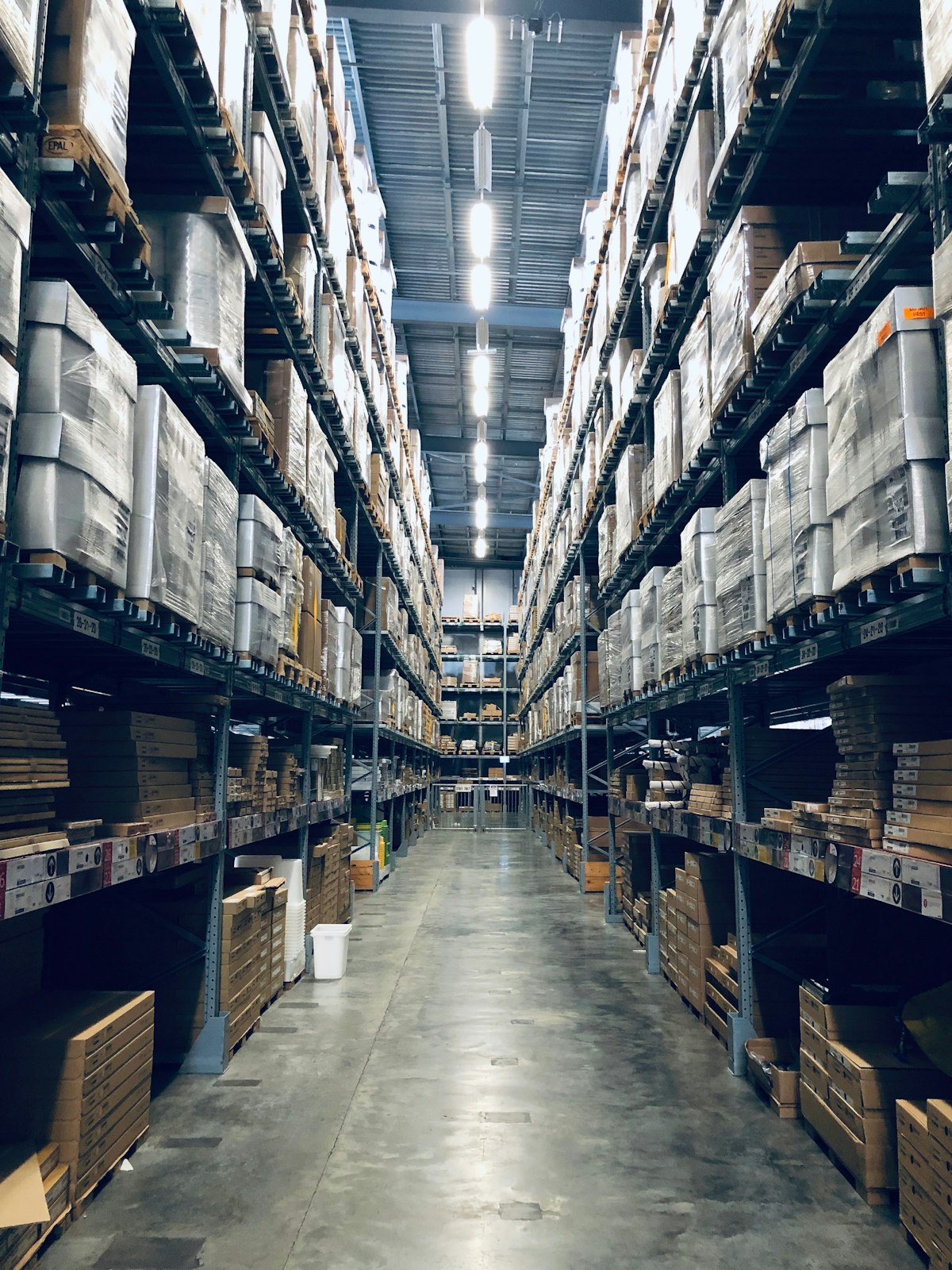 Tall selective pallet racking loaded with palletized goods in a large warehouse aisle